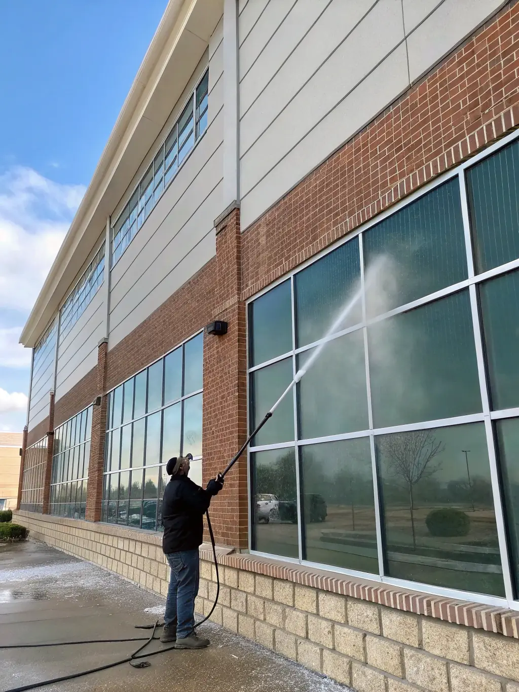 A before-and-after image demonstrating the transformative effect of power washing on a commercial building's exterior, removing dirt and grime.